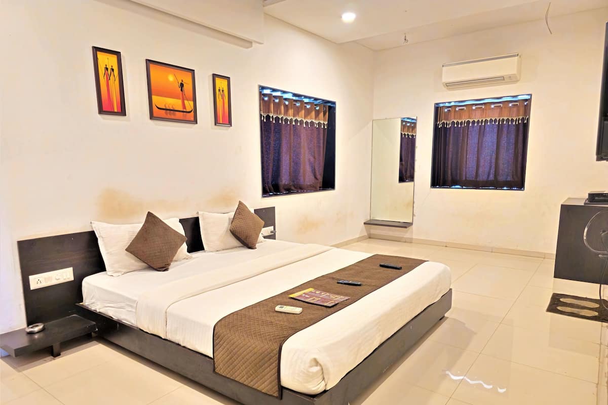 A modern hotel room with a large bed, a bedside table, a mirror, and artwork on the wall.