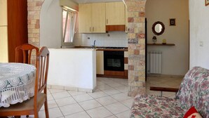 A compact kitchen with an island, wooden cabinets, and a tiled floor.