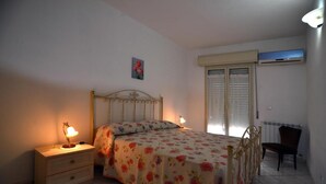 A bedroom with a bed, bedside tables, a chair, and a radiator.
