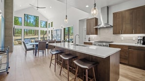 A modern kitchen with a large island, wooden cabinets, and a view of the outdoors. - Modern Family Lodge with Access to Exclusive Golf (Bend)
