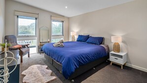 A bedroom with a large bed, two bedside lamps, a chair, a small table, and a window. - Rosebud Township Entertainer (Melbourne)