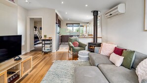 A modern living room with a sofa, TV, and fireplace. - Rosebud Township Entertainer (Melbourne)