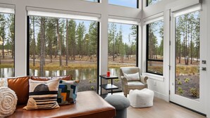 A modern interior with a large window overlooking a forest and a body of water. - Modern Nature Retreat with Access to Exclusive Golf (Bend)