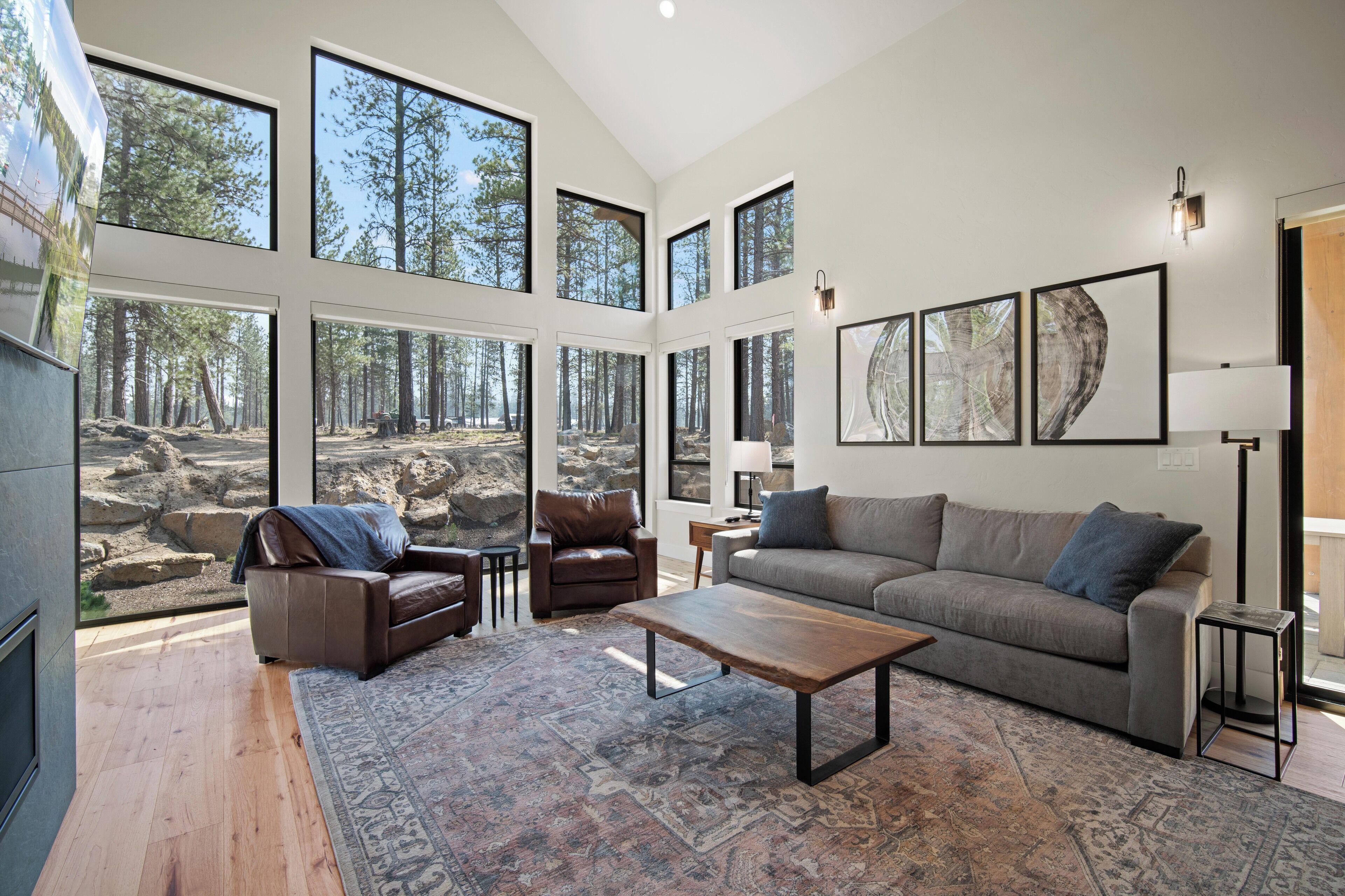 A spacious living room with large windows, a fireplace, a sofa, a coffee table, and a rug.