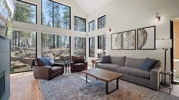 A spacious living room with large windows, a fireplace, a sofa, a coffee table, and a rug.