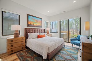 A bedroom with a large bed, wooden dresser, and a desk with a lamp.