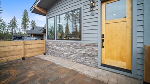 Une maison moderne avec une façade en pierre et en bois, de grandes fenêtres et une porte en bois.