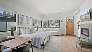 A modern bedroom with a bed, bedside table, lamp, and a TV mounted on the wall. - Forestbrook Hideaway with Access to Forest House (Bend)