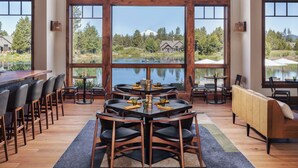 A spacious dining area with a high ceiling, large windows, and a view of a lake. - Forestbrook Hideaway with Access to Forest House (Bend)