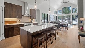 Una cocina moderna con una isla grande, armarios de madera oscura y una campana extractora central.
