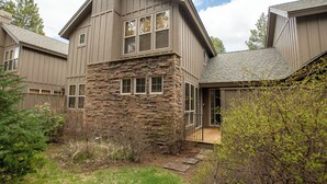 Una casa moderna de dos pisos con fachada de piedra, ventanas amplias y un jardín cuidado.