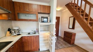 A compact kitchen with wooden cabinets, a microwave, a refrigerator, and a sink.