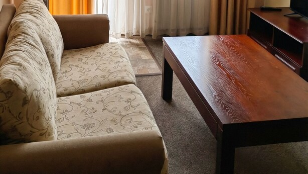 A living room with a sofa, a wooden coffee table, and a television. - Mountain Paradise 2 - Cosy Mountain View Apartment - 200mbps Wifi (Bansko)