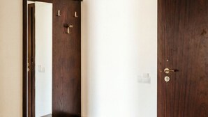 A room with a wooden dresser, a large mirror, and a dark wooden door. - Mountain Paradise 2 - Cosy Mountain View Apartment - 200mbps Wifi (Bansko)