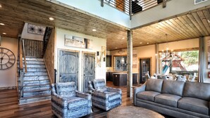 A spacious living area with a wooden staircase, a large sofa, and a coffee table.