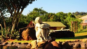 A statue of a seated figure in a garden setting with a house and trees in the background. - Mulberry Lane Suites (Graskop)