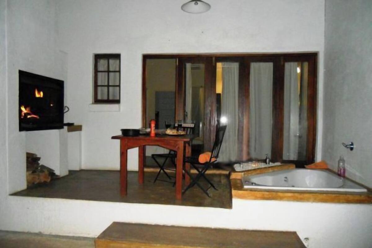A room with a fireplace, a dining table with chairs, a large window, and a bathtub.