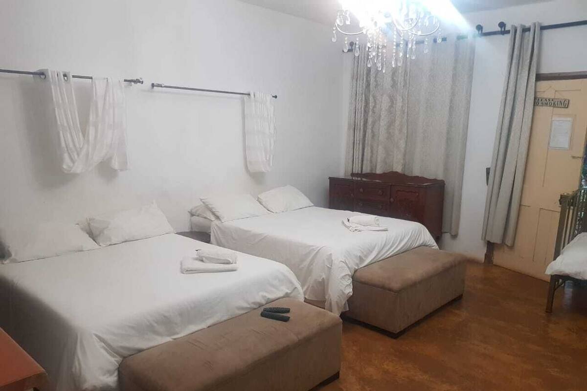 A hotel room with two beds, a wooden dresser, and a chair.