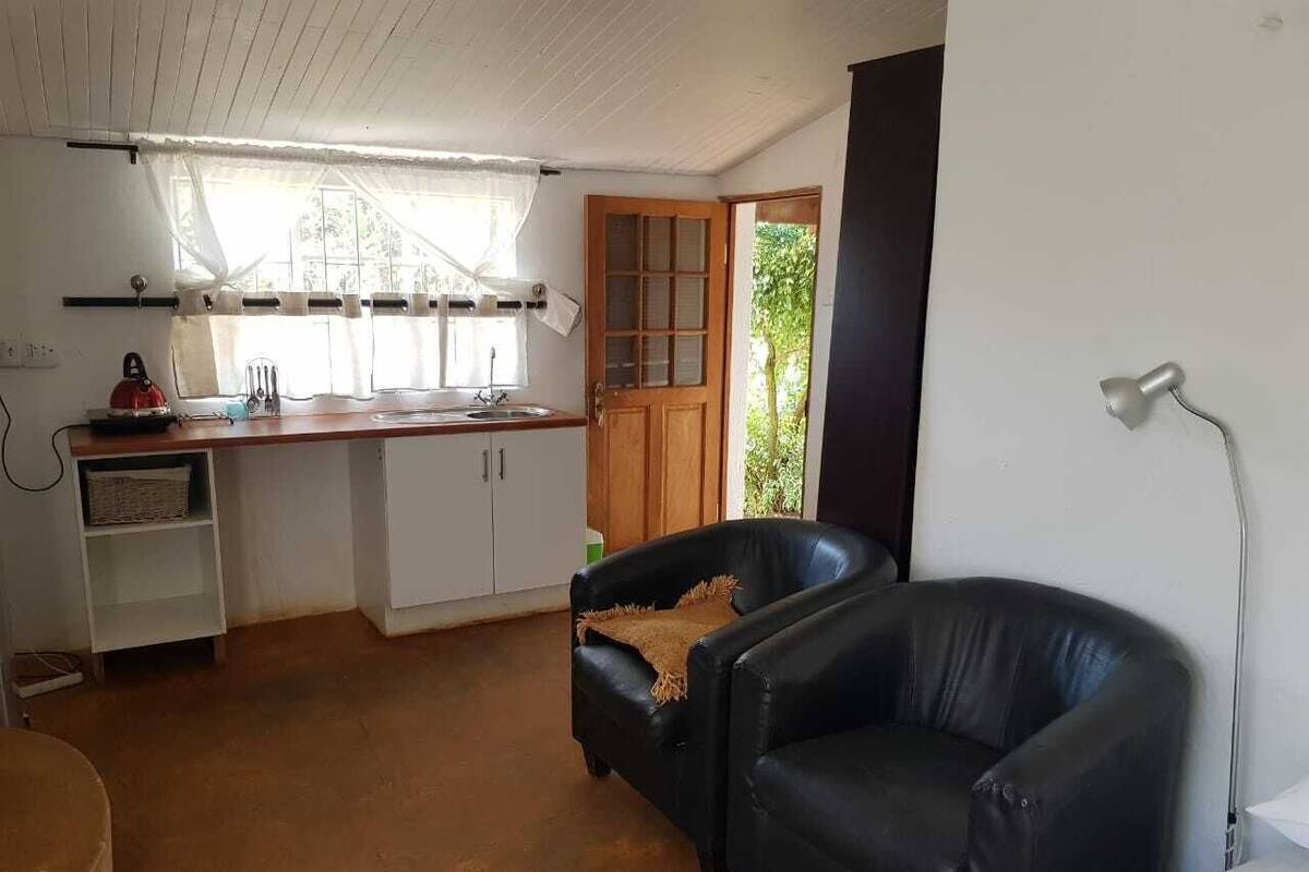 A compact living space with a kitchenette, a black leather sofa, and a dining table.