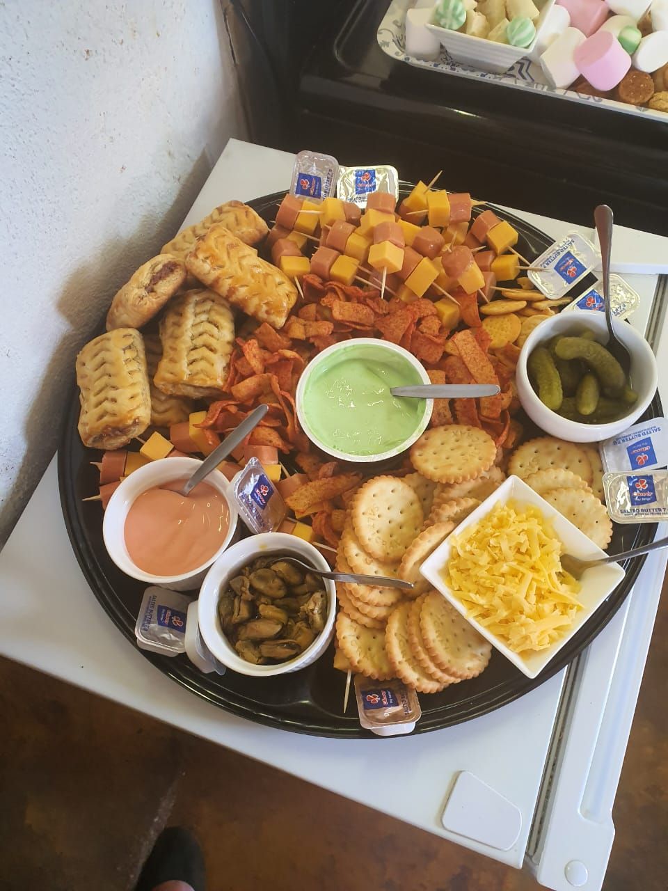 A platter with various snacks including cheese, crackers, and dips.