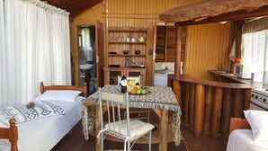 A cozy room with two beds, a dining table with a chair, a kitchen area, and a bathroom visible through an open door. - Mulberry Lane Suites (Graskop)