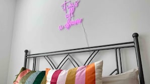 Ein Bett mit Metallgestell und einem Neonzeichen darüber.