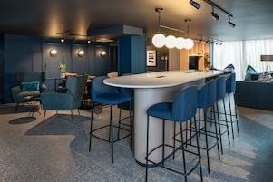 A modern bar area with a central island, bar stools, and ambient lighting.