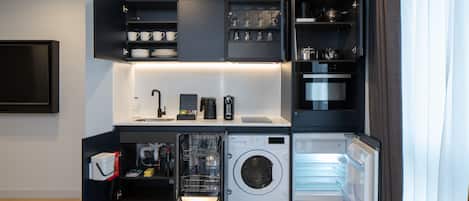 Eine kompakte Küche mit integrierten Geräten, darunter ein Geschirrspüler, eine Waschmaschine und ein Kühlschrank.