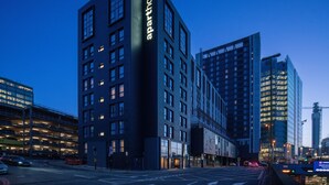 Un edificio moderno de varios pisos con un llamativo letrero de 'aparthotel'.
