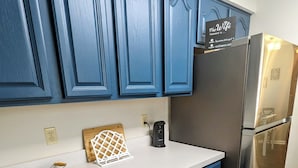 Een keuken met blauwe kastjes, een roestvrijstalen koelkast en een wit aanrecht.