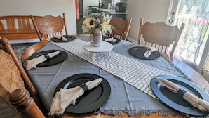 Een eettafel gedekt met borden, servetten en een middelpunt.