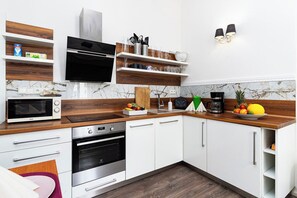 A modern kitchen with white cabinets, wooden countertops, a built-in oven, a microwave, and a coffee maker.