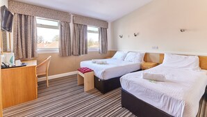 A hotel room with two beds, a desk, a chair, a small stool, and a window with curtains.