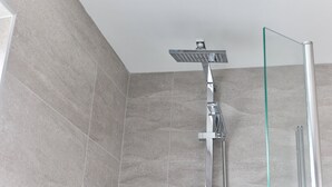 A shower with a glass enclosure, a chrome showerhead, and a wall-mounted control panel. - Properties Unique | Dene Rooms Triple 29 (Newcastle Upon Tyne)