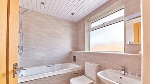 Une salle de bain avec une baignoire, des toilettes, un lavabo et une fenêtre.