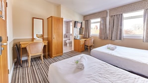 Une chambre d’hôtel avec deux lits, un bureau, une chaise, une armoire, une salle de bain et un téléviseur.