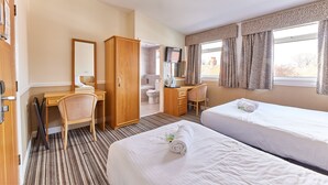 A hotel room with two beds, a desk, a chair, a wardrobe, a bathroom, and a TV.