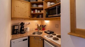 Una cucina compatta con mobili in legno, un forno a microonde, una macchina da caffè e un lavastoviglie.