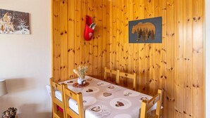 Zona pranzo con parete in legno, tavolo con tovaglioli a motivi floreali e un vaso con fiori.