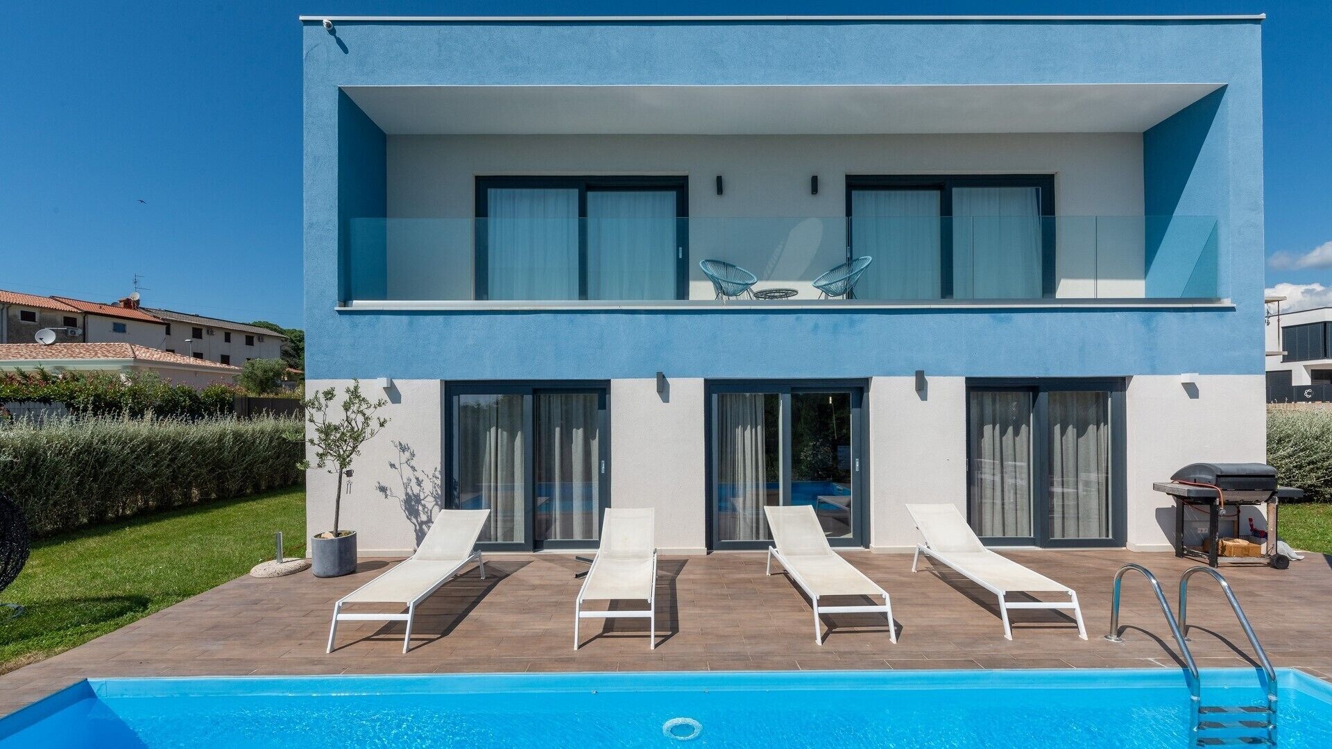 Un bâtiment moderne à deux étages, doté d’une piscine, d’un espace extérieur aménagé et offrant une vue dégagée sur les environs.