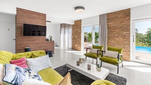 A modern living room with a sofa, chairs, a coffee table, and a TV.