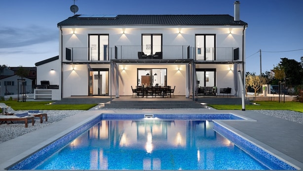 A two-story house with a swimming pool in the front.