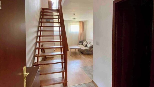 Un escalier menant à un espace de vie comprenant un canapé et une table.