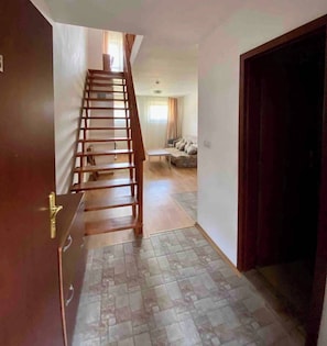 Un escalier menant à un espace de vie comprenant un canapé et une table.