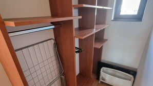 A compact room with a wooden wardrobe, a radiator, and a window. - 1BR Homey Duplex 300mbps Wifi 2 Floor With Washer (Bansko)