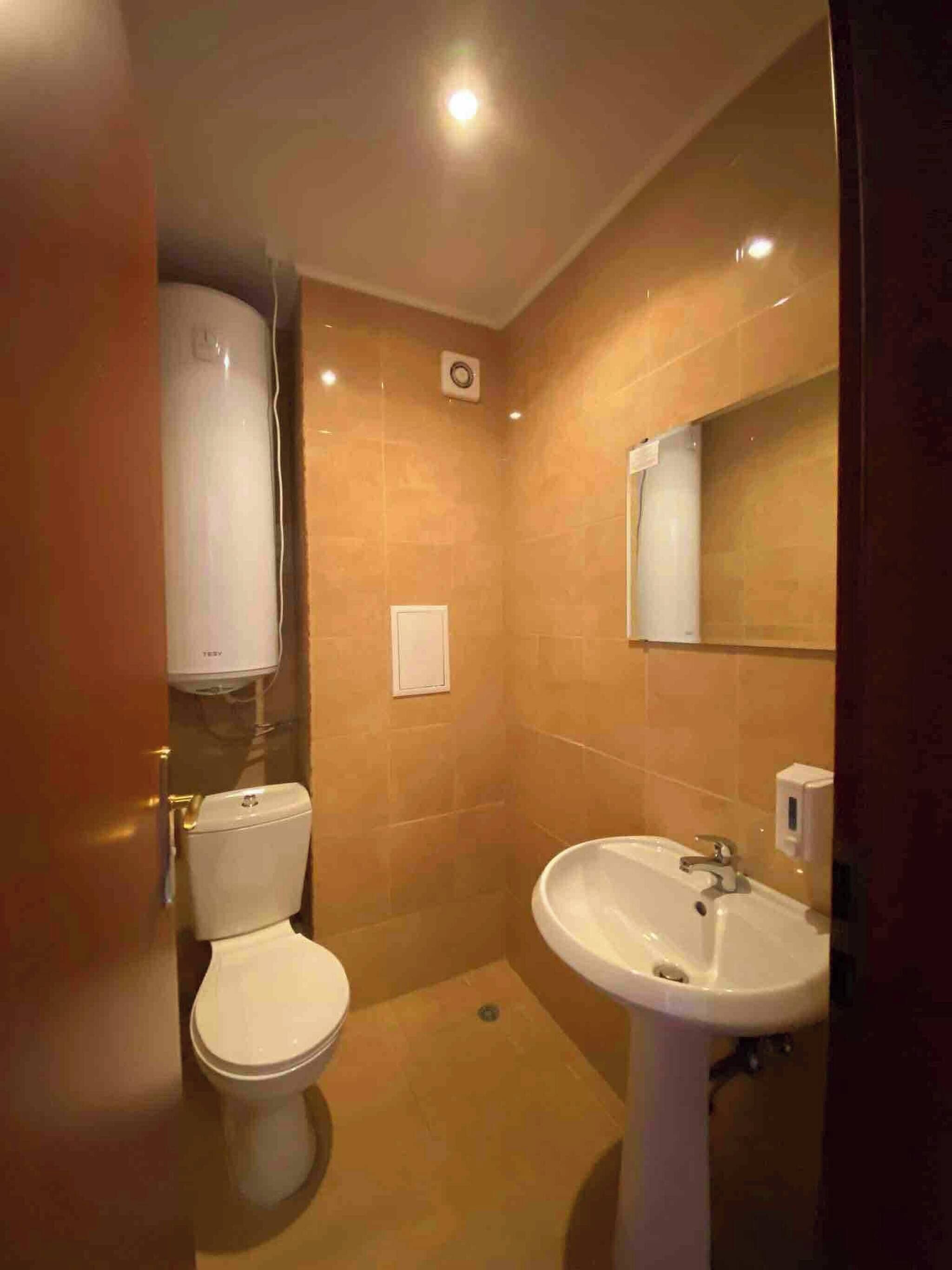 A bathroom with a toilet, sink, and mirror.