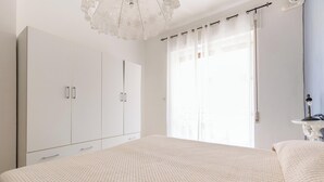 Un dormitorio con una cama grande, un armario y una ventana con cortinas.