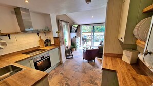 Eine moderne Küche mit Holz Arbeitsplatte, eingebautem Ofen und einem Essbereich mit Tisch und Stühlen.