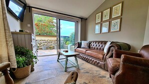 Ein Wohnzimmer mit braunem Ledersofa, einem Holztisch und einer Steinwand.