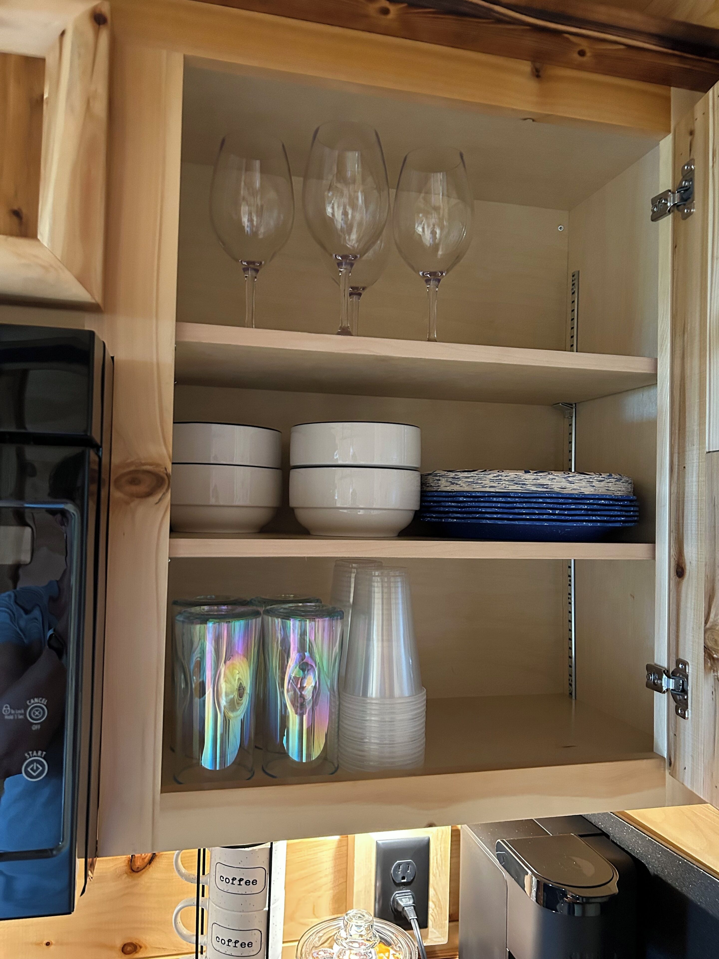 Un mueble de madera con estantes que contienen copas de vino, cuencos y platos.